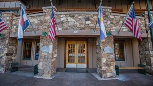 Un bâtiment en pierre avec une porte en bois et plusieurs drapeaux américains.