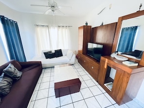 A modern living room with a sofa, TV, and wooden cabinet.