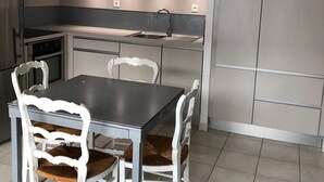 Una cucina moderna con zona pranzo, caratterizzata da un'isola centrale, mobili bianchi e un lampadario.
