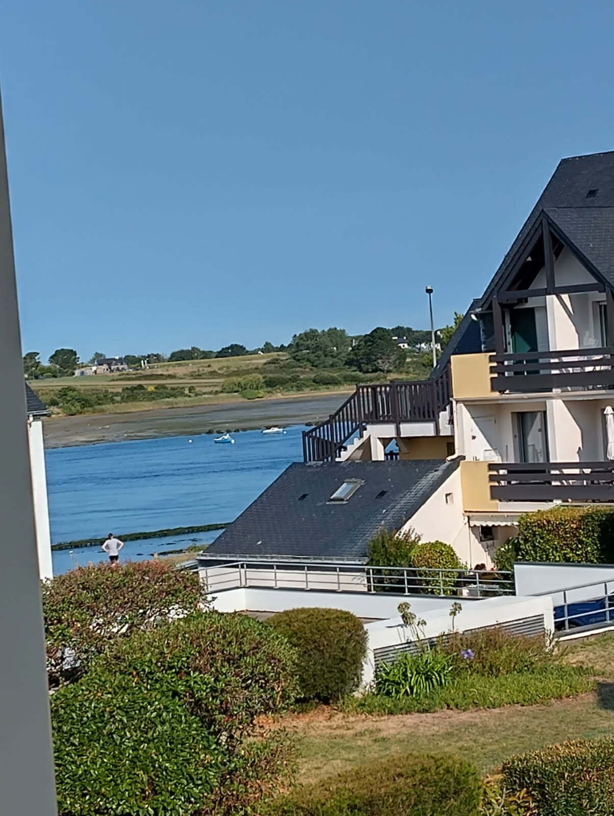 Un bâtiment moderne doté d’un toit plat et d’un balcon donnant sur une étendue d’eau.