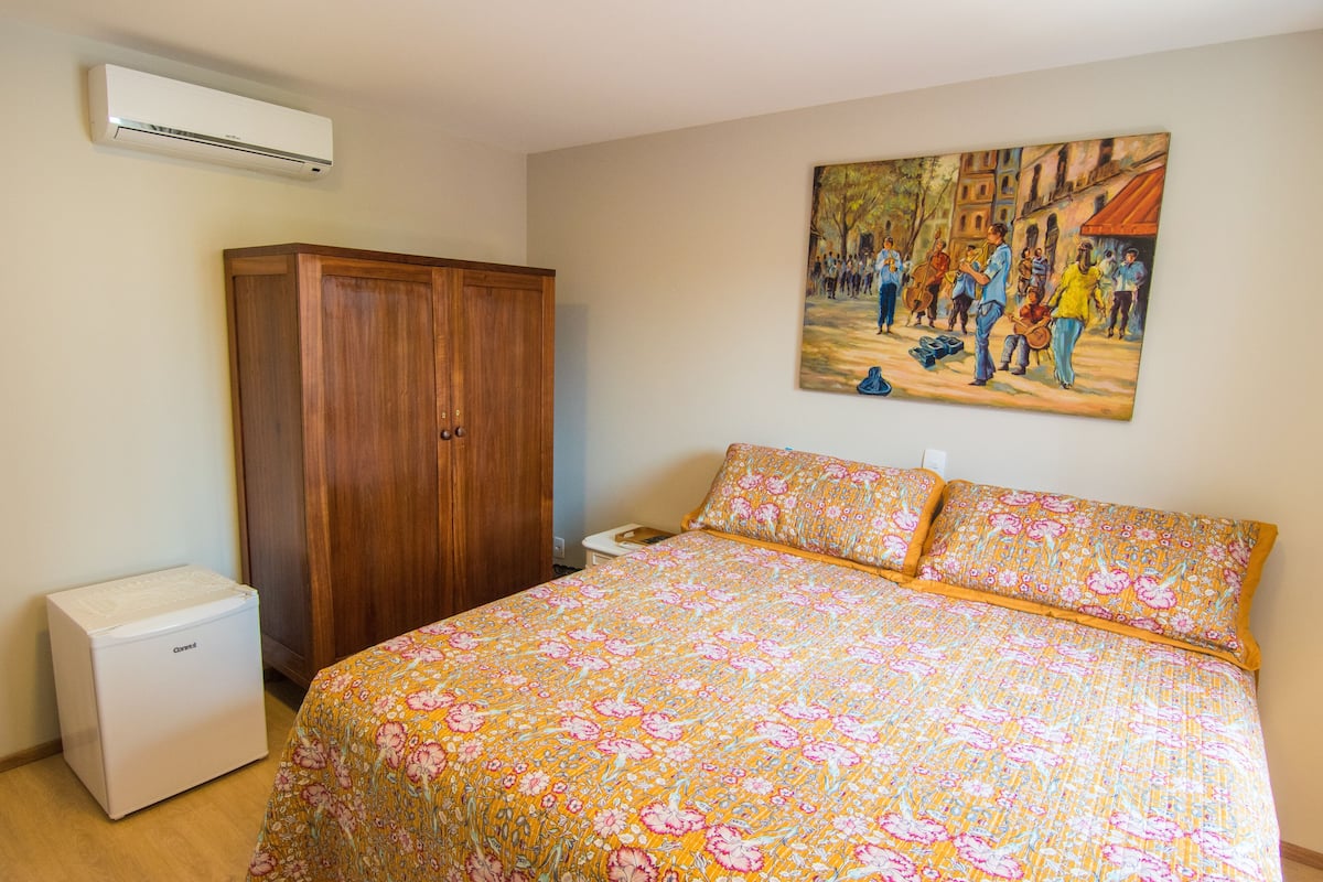 Ein Schlafzimmer mit Bett, Klimaanlage, Kleiderschrank und einem Gemälde an der Wand.