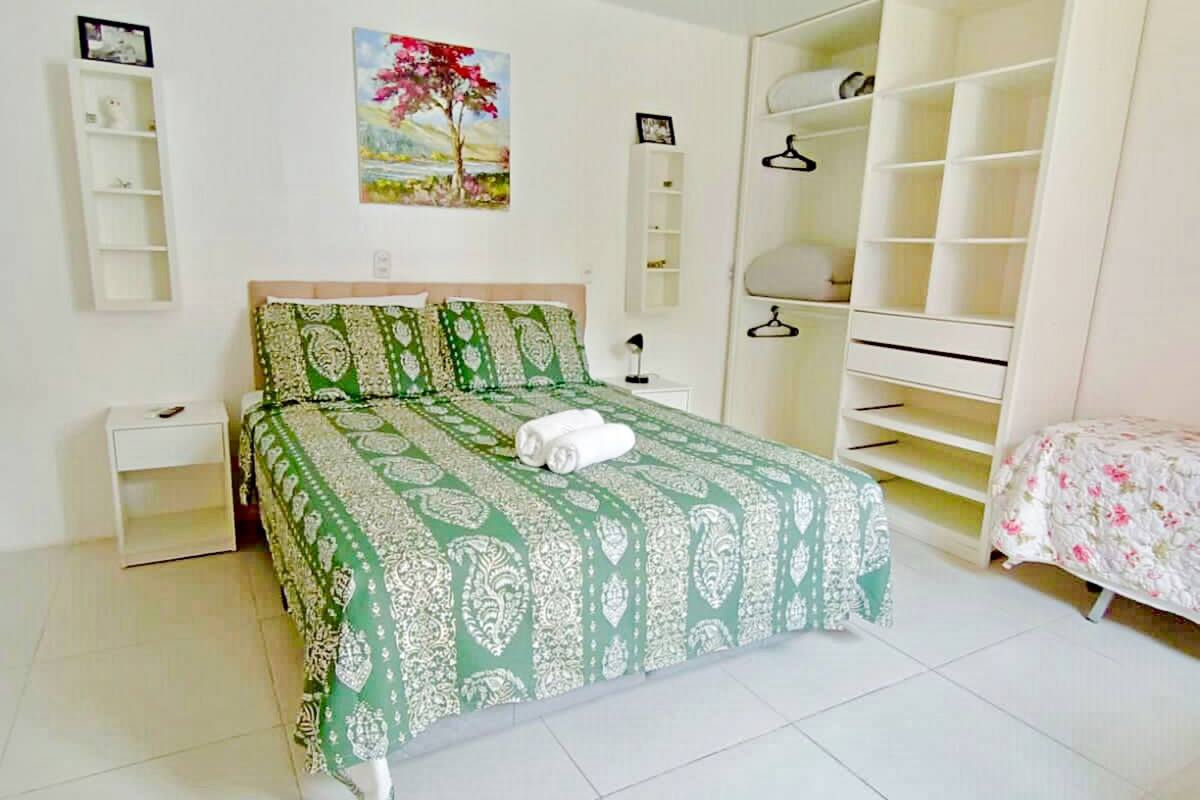 Ein Schlafzimmer mit Bett, Nachttisch, Kleiderschrank und einem Gemälde an der Wand.