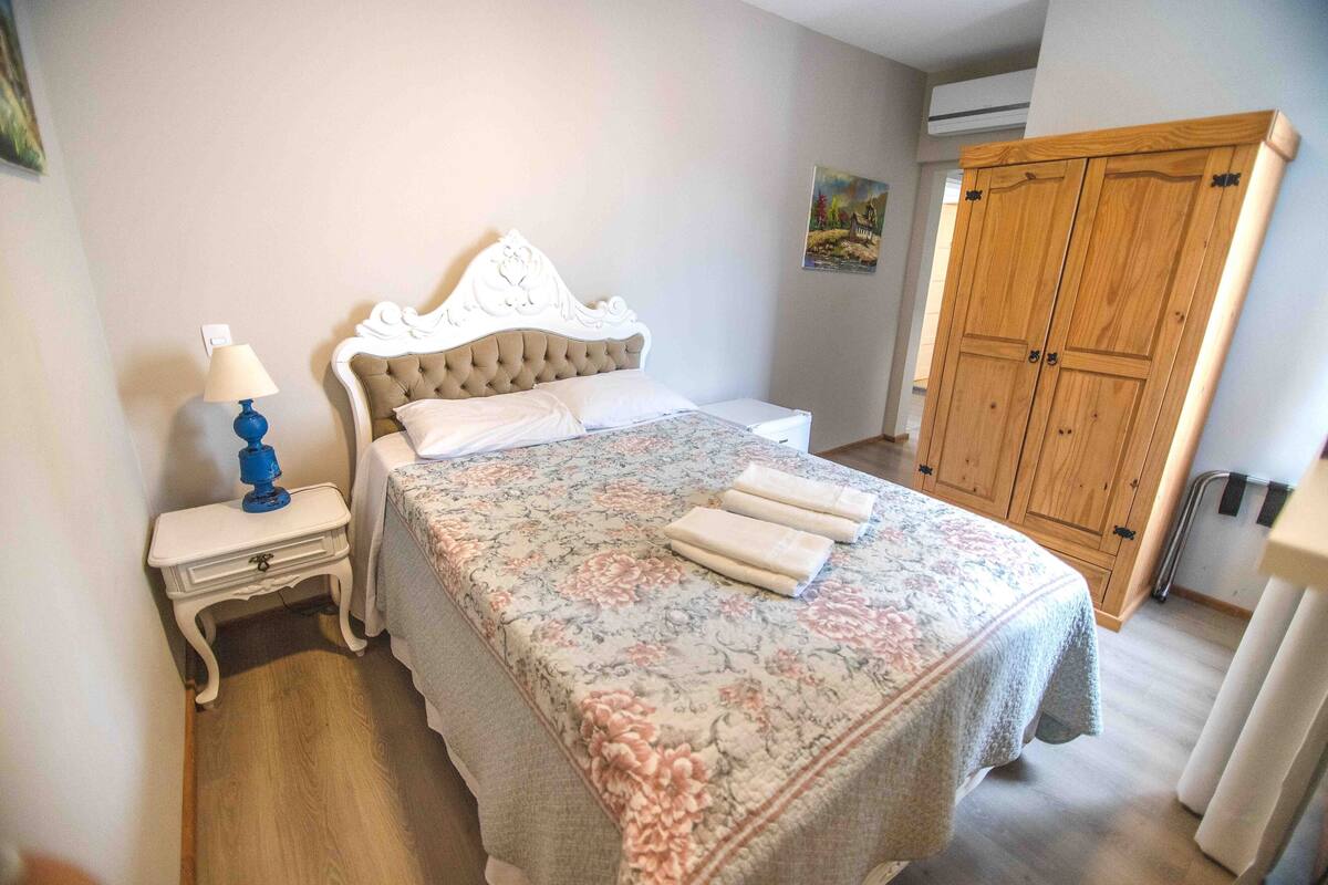 Ein Schlafzimmer mit Bett, Nachttisch, Lampe und Kleiderschrank.
