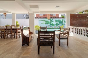 A spacious patio with wooden furniture, a pool, and a mural of palm trees. - Hospedaria Conceitual (Florianópolis)