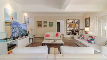 A living room with a TV, sofa, coffee table, and artwork on the walls.
