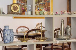 A dining table with chairs, a clock, decorative vases, and a tray with metal containers. - Hospedaria Conceitual (Florianópolis)