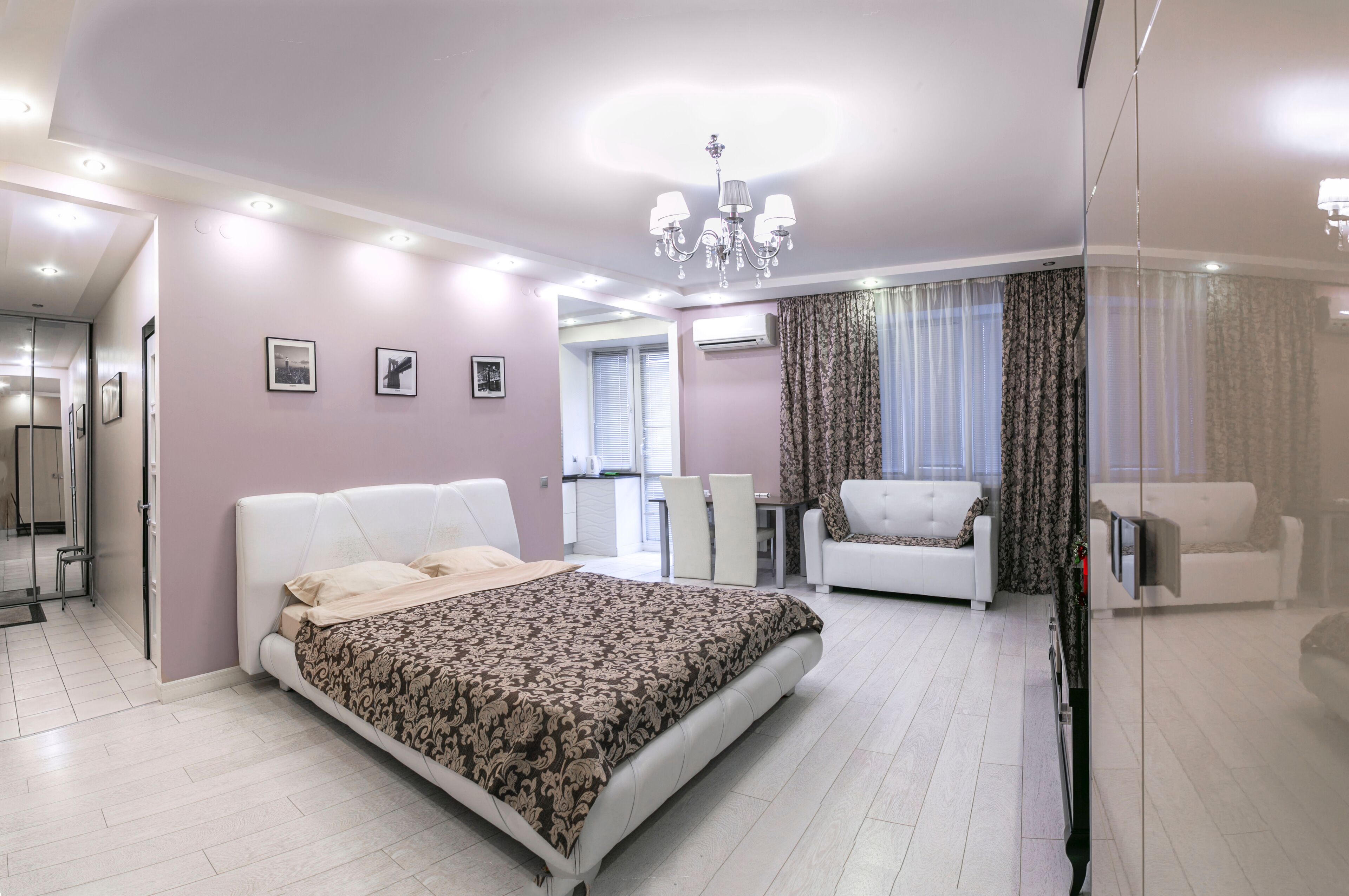 Une chambre moderne avec un grand lit, un lustre et un coin salon comprenant un canapé et des fauteuils.