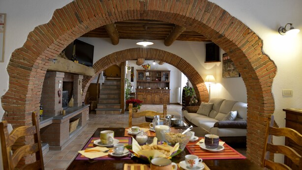 A dining area with a brick archway, wooden furniture, and a table set for a meal. - LAST-MINUTE!FANTASTIC PART OF RUSTIC IN THE VIEW ONLACOLLINE WITH PRIVATE POOL (Massarosa)