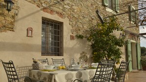 An outdoor dining area with a table set for four, surrounded by metal chairs, against a stone wall with a window and a decorative wall piece. - LAST-MINUTE!FANTASTIC PART OF RUSTIC IN THE VIEW ONLACOLLINE WITH PRIVATE POOL (Massarosa)
