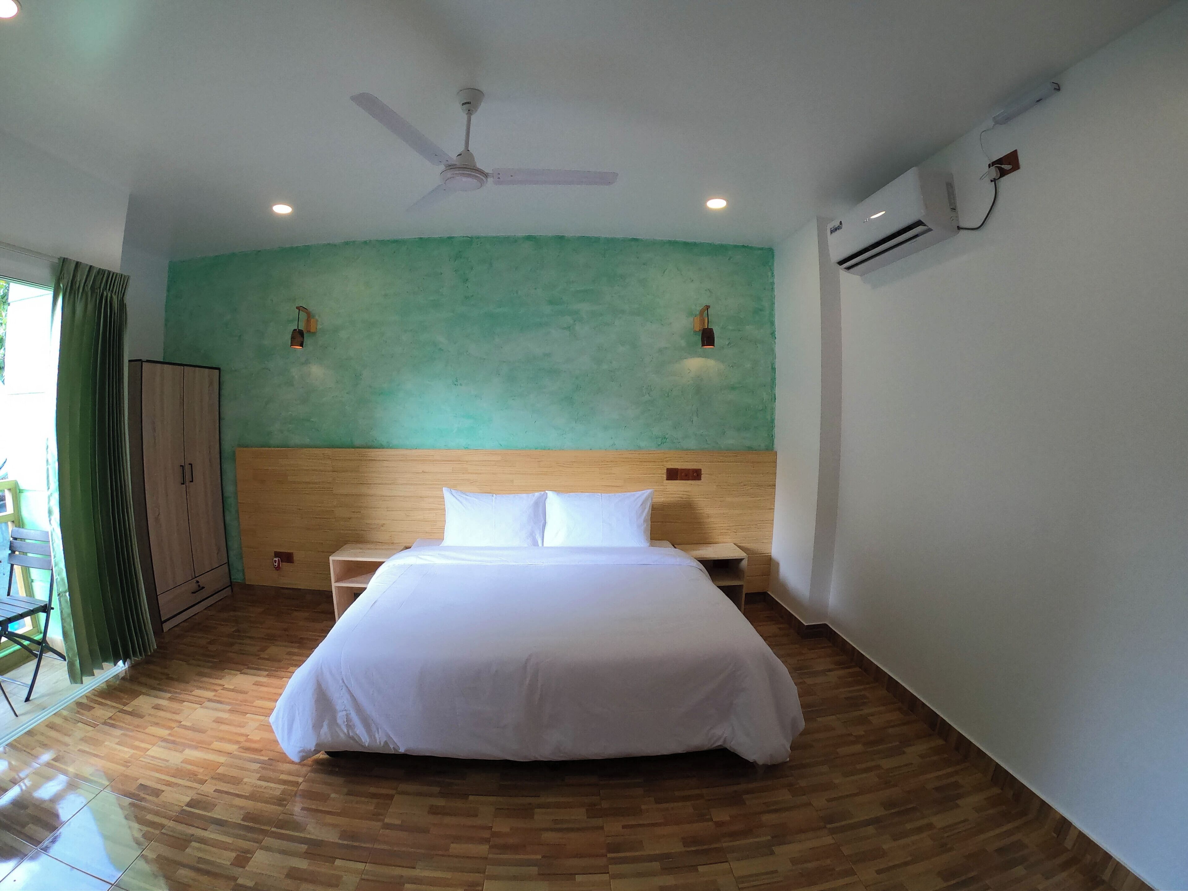 A bedroom with a large bed, wooden headboard, two bedside tables, a ceiling fan, and an air conditioning unit.