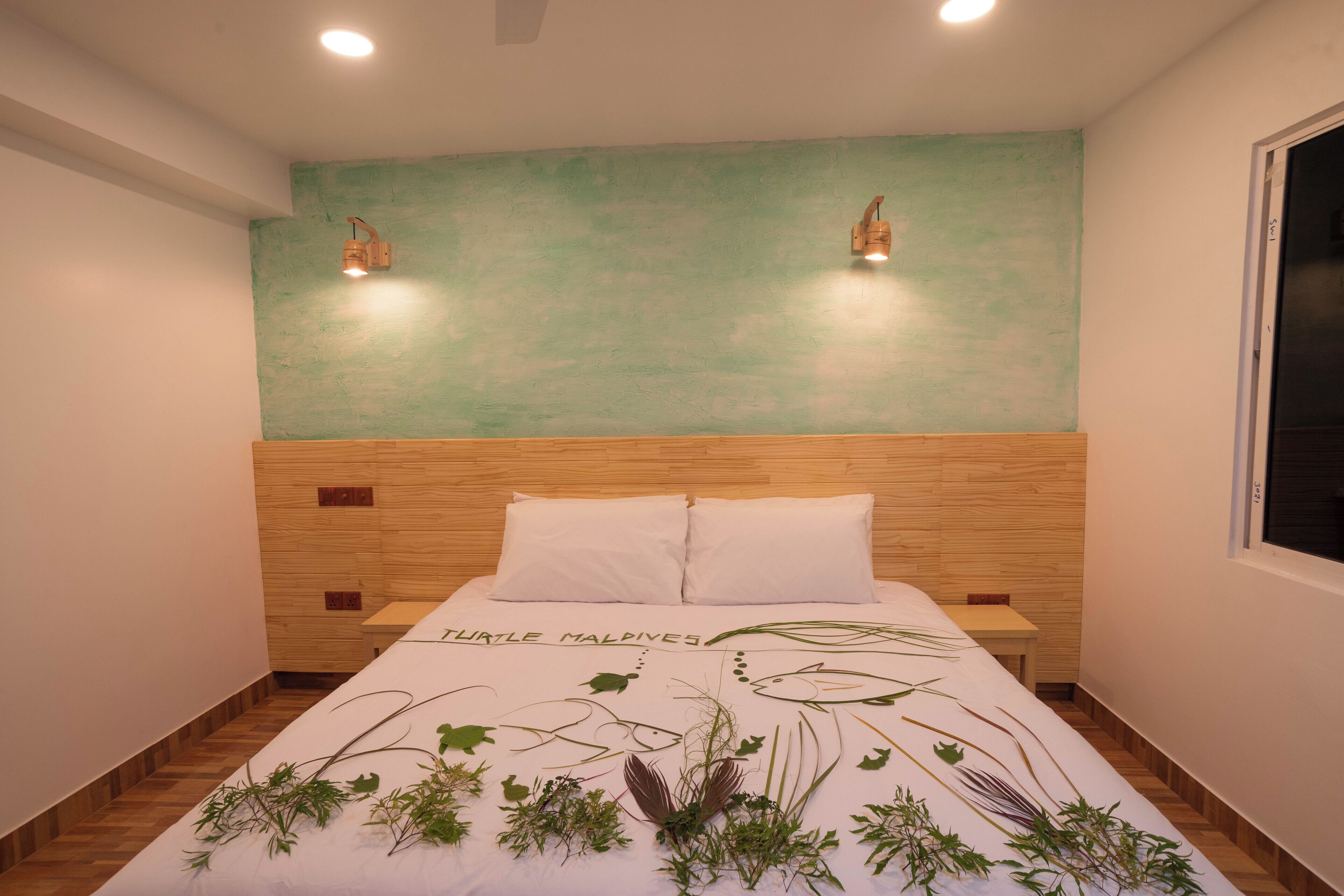 A bedroom with a bed, two wall-mounted lights, a wooden headboard, and a wall painted in a light teal color.
