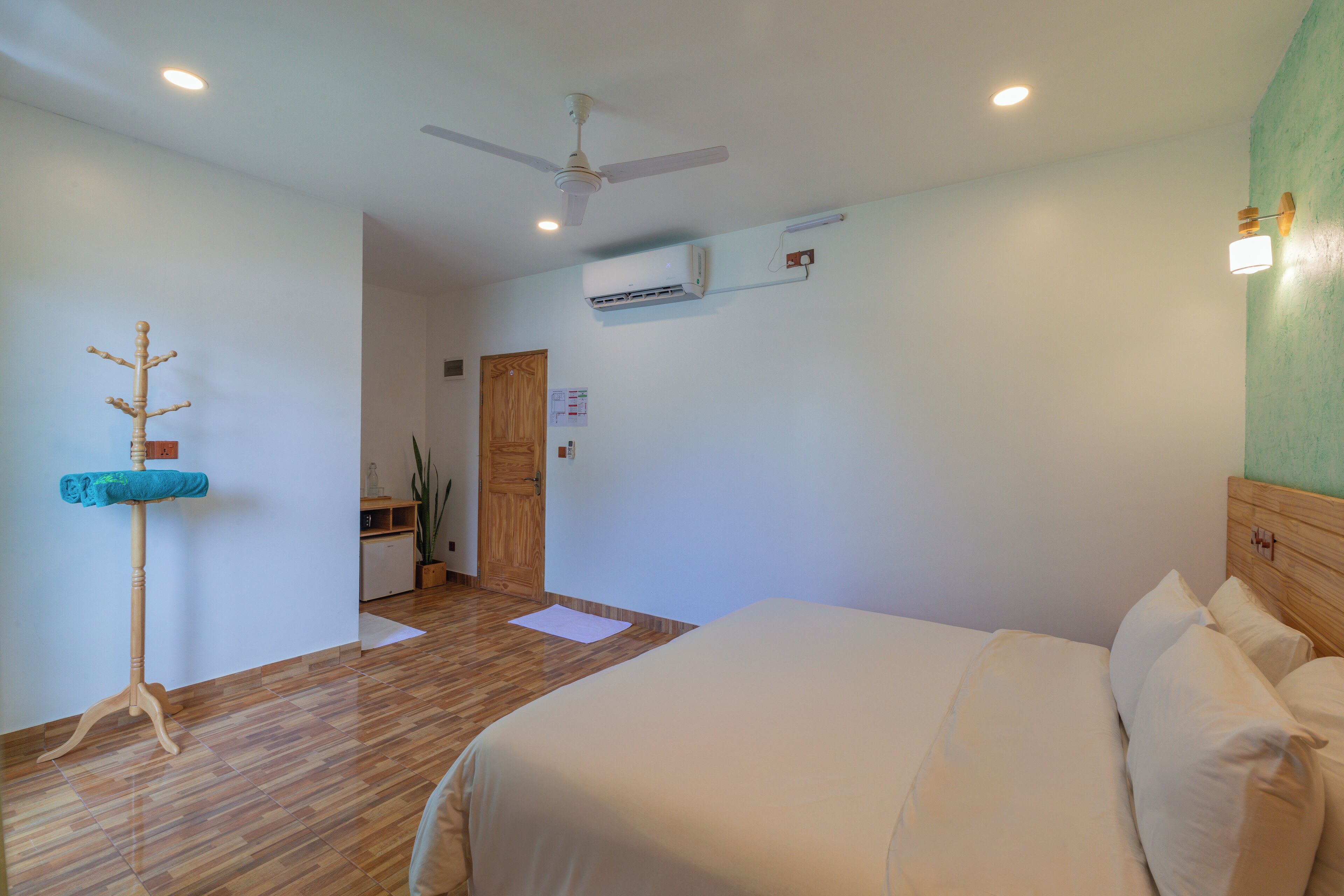 A bedroom with a bed, a ceiling fan, an air conditioning unit, and a wooden headboard.