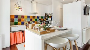 Une cuisine moderne avec un mur de crédence aux couleurs vives, des meubles blancs et un îlot central doté de tabourets.