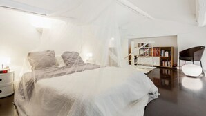 Une chambre à coucher avec un grand lit, une table de chevet, une bibliothèque et une chaise.