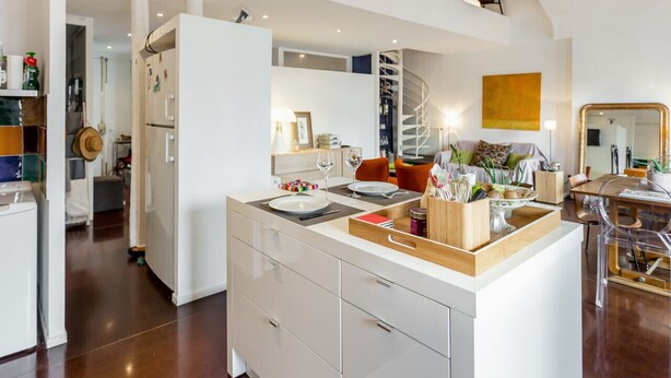 Une cuisine moderne dotée d’un îlot central, de meubles blancs et d’un escalier en colimaçon.