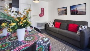A modern living room with a grey sofa, colorful tablecloth, and a decorative flower arrangement.