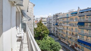 Un immeuble résidentiel à plusieurs étages, doté de balcons, d’une façade en pierre et offrant une vue dégagée sur les environs.