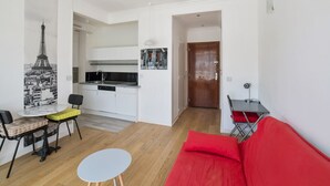 Un espace de vie compact comprenant une cuisine, un coin repas et un canapé rouge.