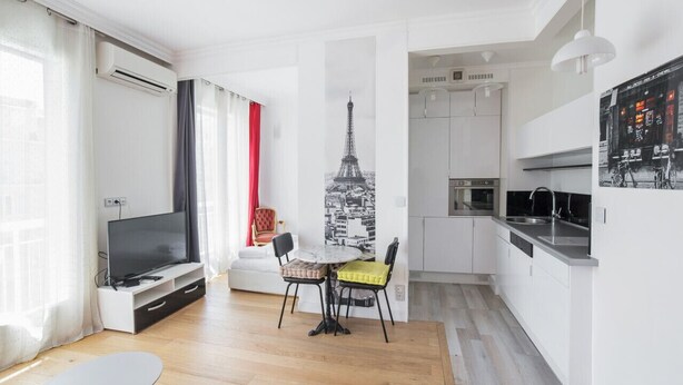 Un salon moderne doté d’un téléviseur à écran plat, d’une table à manger avec deux chaises et d’un coin cuisine équipé d’un four à micro-ondes et d’un évier.