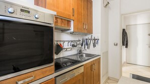 Eine moderne Küche mit Holzschränken, Edelstahlgeräten und einer gefliesten Spritzschutzwand.
