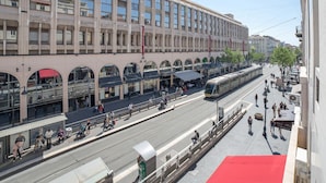 A modern building with multiple floors, large windows, and a tram line running alongside it.