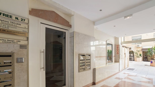 A clean, modern hallway with a glass door leading to a room, a mail slot, and a directory on the wall.