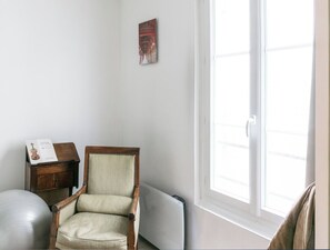 Simple, serene space with a single chair, bookshelf, and large window.