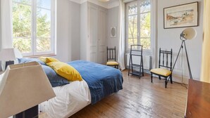 Ein Schlafzimmer mit einem Bett, zwei Stühlen, einer Lampe und einer Stehlampe.