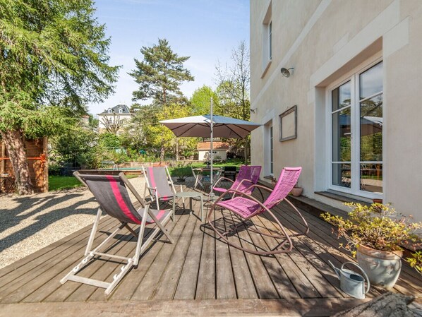 An outdoor deck with wooden flooring, a table, and four chairs.