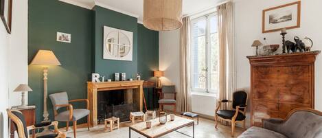 Una sala de estar acogedora con chimenea, asientos cómodos y un ventanal con cortinas.