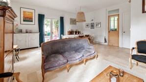 Ein geräumiges Wohnzimmer mit grauem Sofa, Couchtisch aus Holz und einem Essbereich mit Tisch und Stühlen.