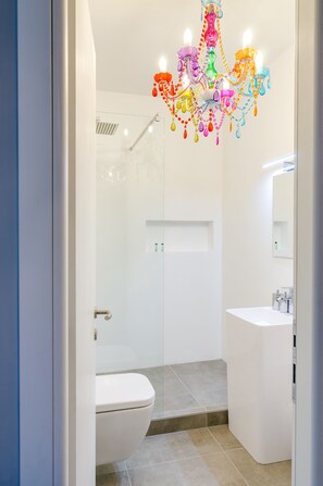 Een moderne badkamer met een wit toilet, een douchecabine van glas en een witte wastafel.