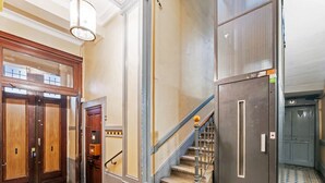 A hotel lobby with a staircase, wooden doors, and patterned flooring. - Appartement Majorel - Welkeys (Lyon)