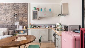 A modern kitchen with a stone wall, a wooden dining table, and a pink refrigerator.