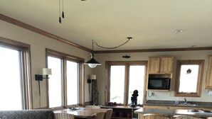 Een ruime woonkamer met een eettafel, twee banken en een keuken met houten kasten en een magnetron.