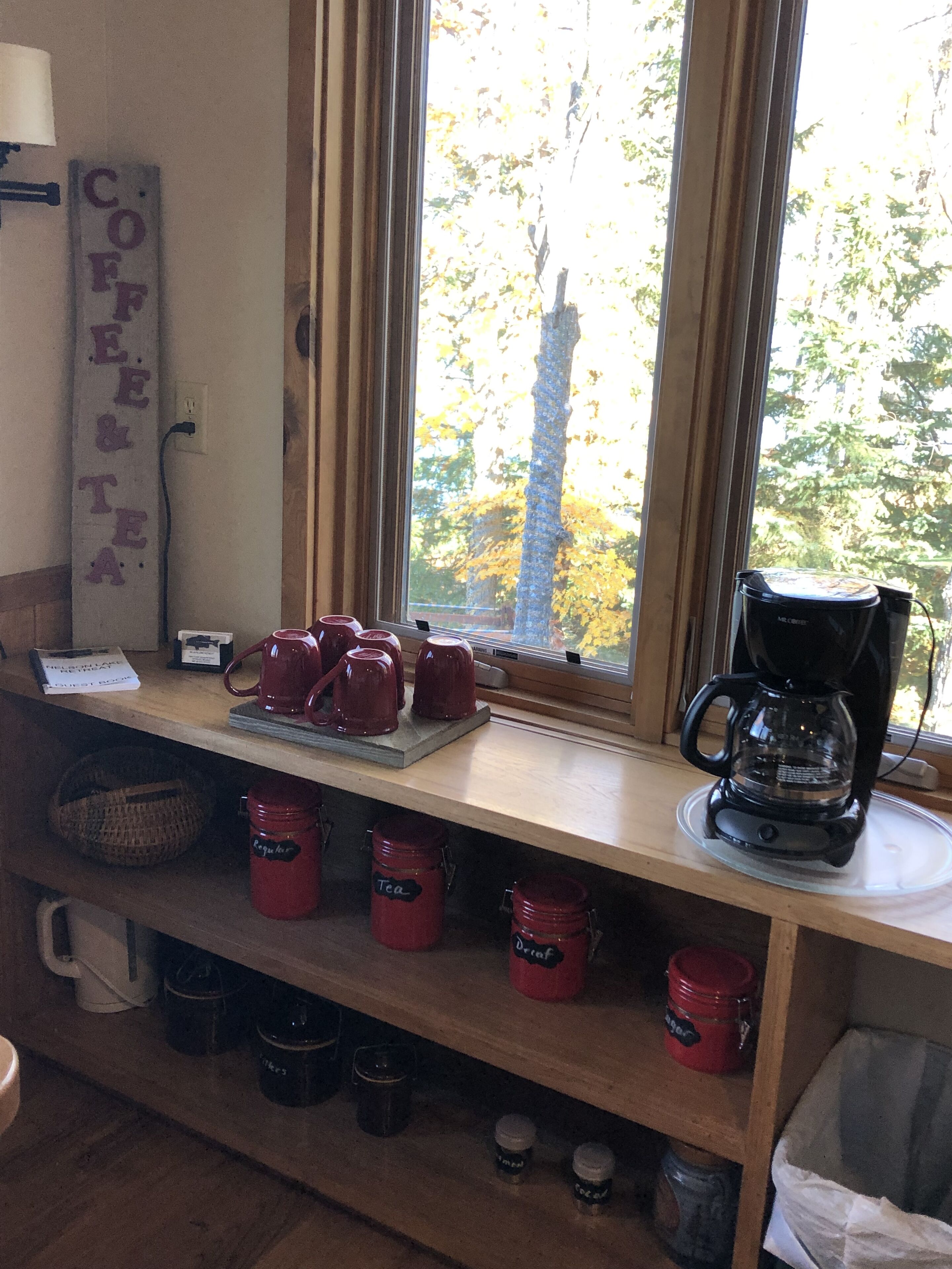 Une cuisine équipée d’un coin café, comprenant une machine à café, des tasses et des boîtes à thé.