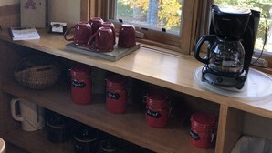 Een keuken met een koffiehoek, inclusief een koffiezetapparaat, mokken en theevoorraad.