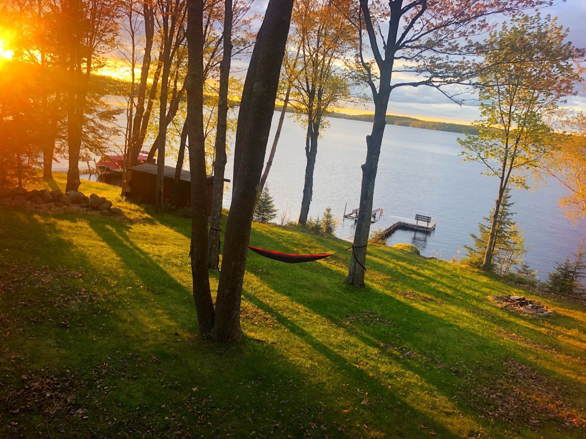 Une vue sur le lac, avec des arbres, un hamac et une jetée.