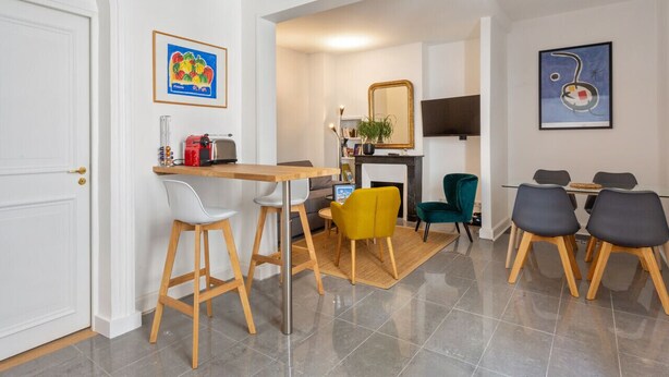 A modern living room with a dining area, a fireplace, and a TV. - Appartement du Marché St Honoré - Welkeys (Paris)