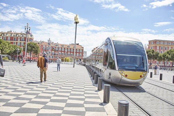 A modern train station with a checkered pavement and a train on the tracks. - Studio Côte Blanche - Welkeys (Nice)