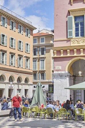 A bustling outdoor café with outdoor seating, surrounded by historic buildings with classic architecture. - Studio Côte Blanche - Welkeys (Nice)