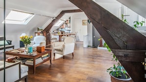 Un salón estilo loft con techo de madera, un comedor y una estantería.