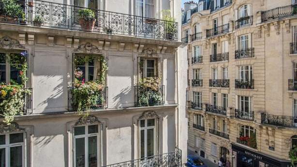 Un edificio de varios pisos con balcones decorados con plantas en macetas.