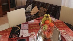 Comedor con una mesa para dos, mantel estampado, jarra de vidrio y frutero.