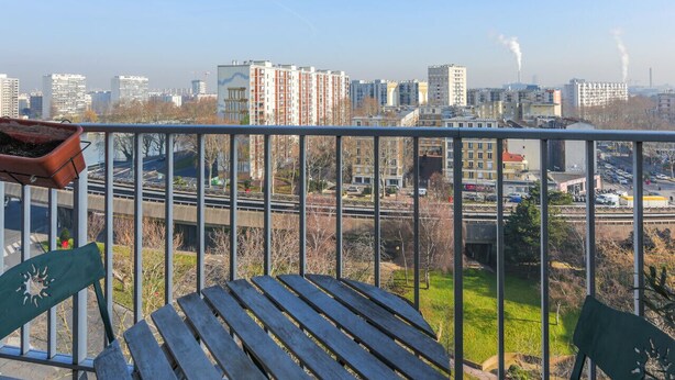 A balcony with a view of a cityscape, including buildings and a highway.