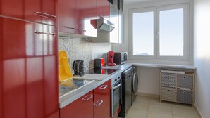 A kitchen with red cabinets, a microwave, a toaster, and a washing machine.