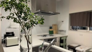 A kitchen with a clear vase containing a plant, a stainless steel sink, and a modern faucet.