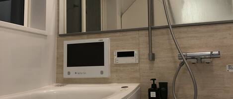 A modern bathroom with a bathtub, a shower, a sink, and a mirror.