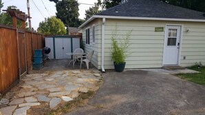 A house with a stone patio, a shed, and a small garden. - Light and bright family-friendly cottage (Portland)