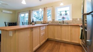 A kitchen with wooden cabinets, a countertop, a refrigerator, and pendant lights. - Light and bright family-friendly cottage (Portland)